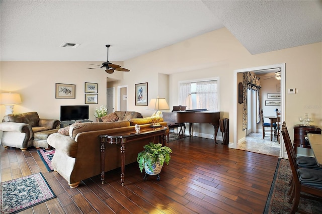 living room featuring ceiling fan, a textured ceiling, wood finished floors, visible vents, and vaulted ceiling