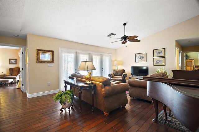 living area featuring dark wood-style flooring, visible vents, vaulted ceiling, a textured ceiling, and baseboards