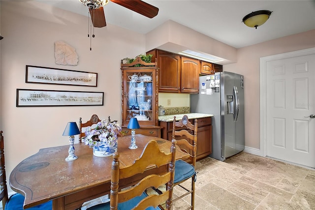 dining room featuring stone finish floor, a ceiling fan, and baseboards