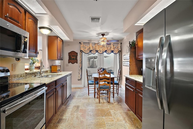 kitchen featuring light stone counters, a sink, visible vents, appliances with stainless steel finishes, and stone tile flooring