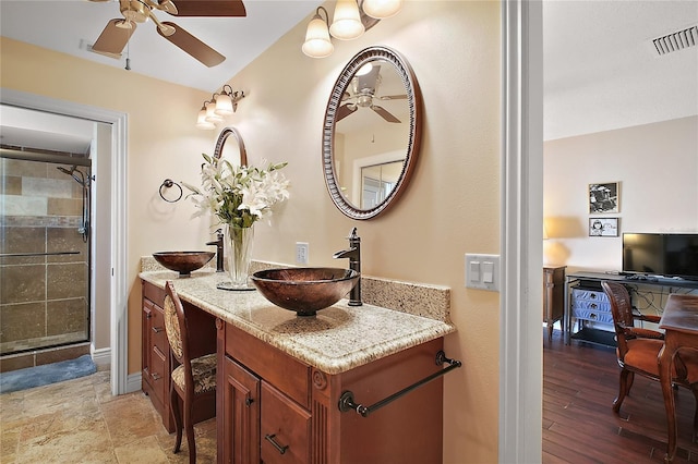 full bathroom with visible vents, a tile shower, ceiling fan, vanity, and baseboards