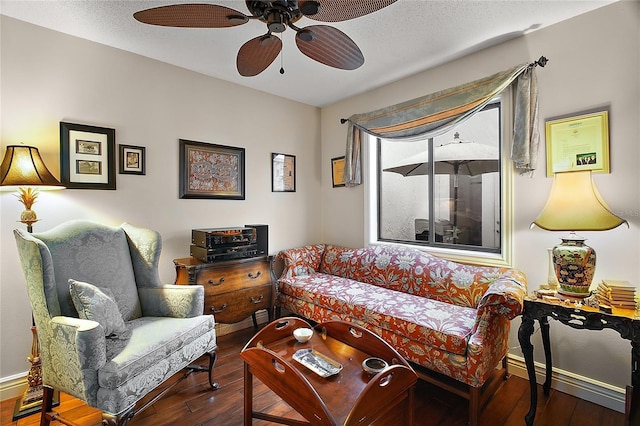 living area with a textured ceiling, baseboards, and wood finished floors