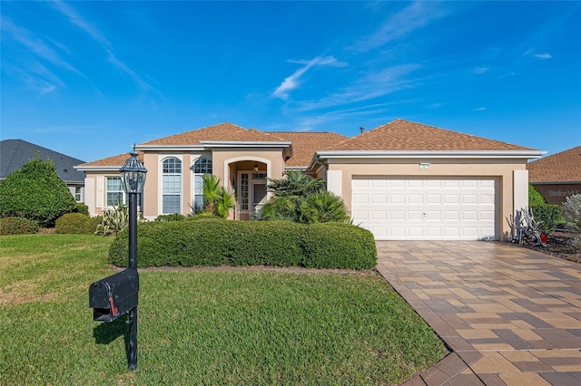 mediterranean / spanish-style home featuring a front lawn, decorative driveway, an attached garage, and stucco siding