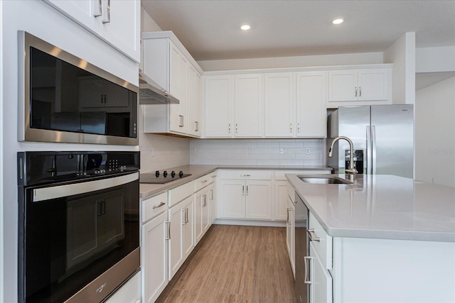 kitchen featuring light countertops, appliances with stainless steel finishes, white cabinetry, a sink, and under cabinet range hood