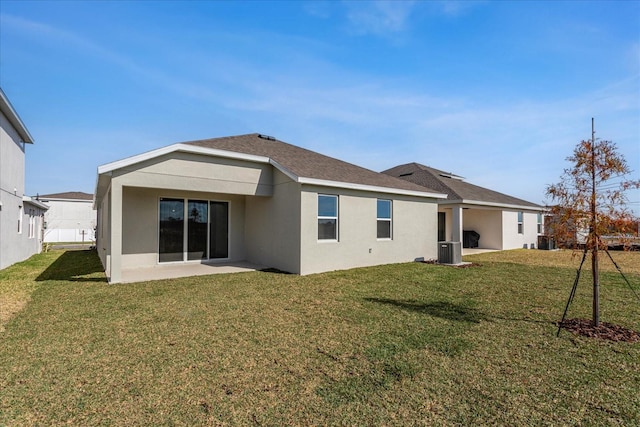 back of house featuring central AC unit, a lawn, a patio, roof with shingles, and stucco siding