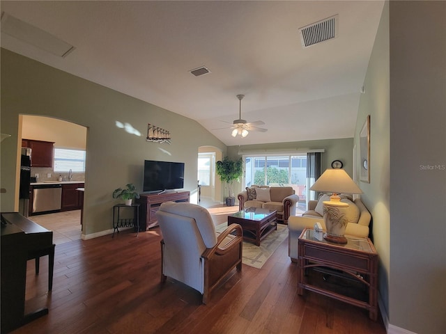 living area with arched walkways, visible vents, lofted ceiling, and wood finished floors