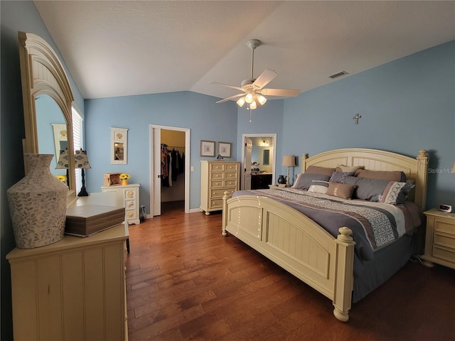 bedroom with dark wood-style flooring, visible vents, a ceiling fan, vaulted ceiling, and a walk in closet