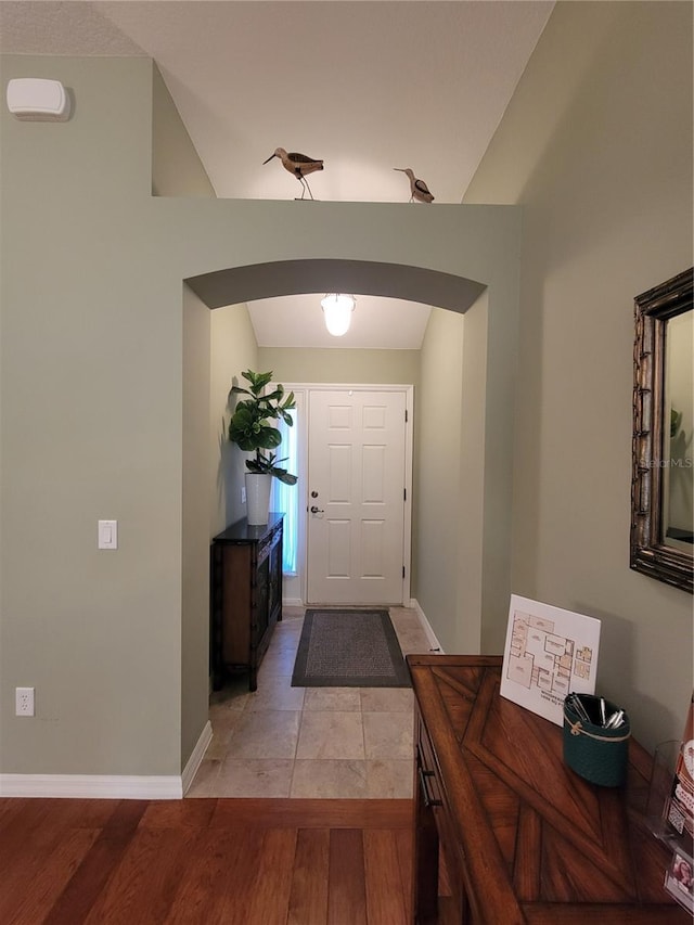 entrance foyer with light wood-style flooring, arched walkways, and baseboards