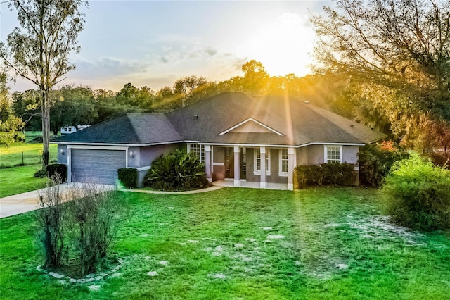 single story home with driveway, a lawn, an attached garage, covered porch, and stucco siding