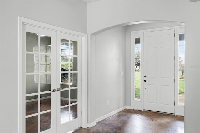 foyer entrance with baseboards, arched walkways, and french doors