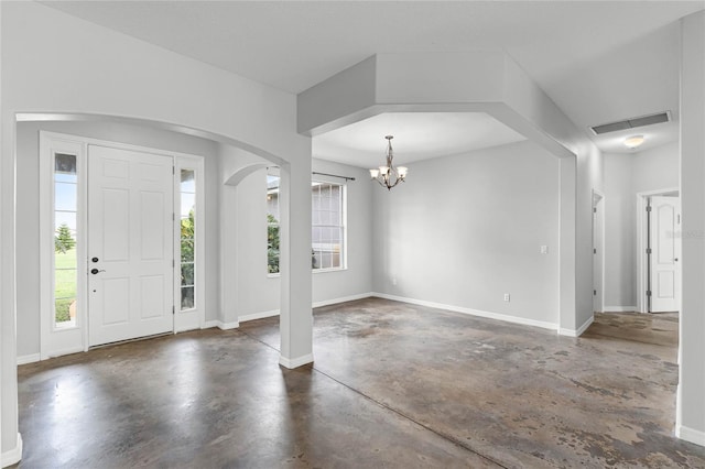 entrance foyer featuring arched walkways, concrete floors, a wealth of natural light, and baseboards