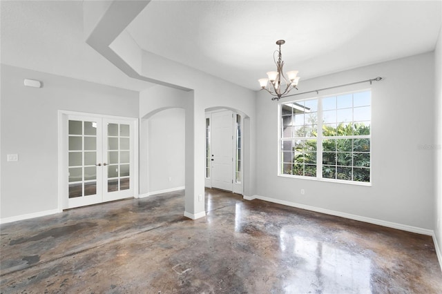 interior space with concrete flooring, arched walkways, a notable chandelier, baseboards, and french doors