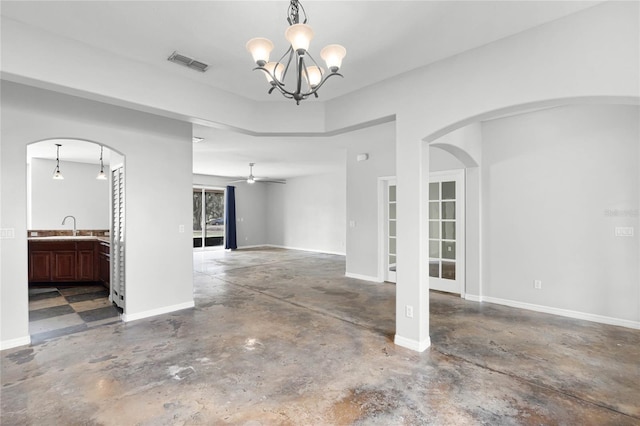 interior space featuring visible vents, a sink, concrete flooring, baseboards, and ceiling fan with notable chandelier