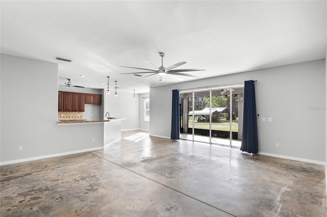 unfurnished living room featuring visible vents, ceiling fan, a textured ceiling, concrete floors, and baseboards