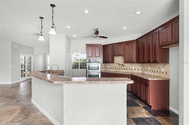 kitchen featuring tasteful backsplash, stainless steel double oven, pendant lighting, and a healthy amount of sunlight