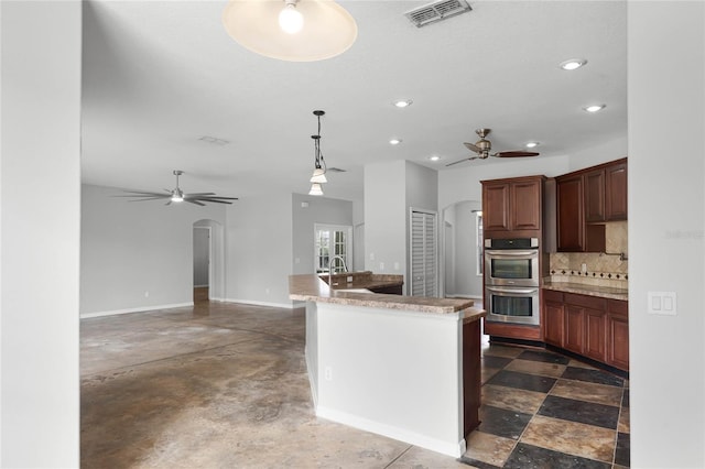 kitchen with visible vents, arched walkways, light countertops, and stainless steel double oven