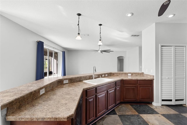 kitchen featuring a ceiling fan, arched walkways, light countertops, and a sink