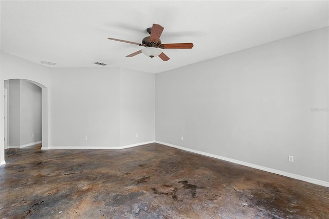 empty room with concrete flooring, arched walkways, baseboards, and a ceiling fan