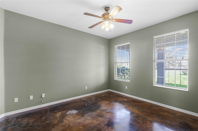 unfurnished room with a ceiling fan, baseboards, and concrete flooring