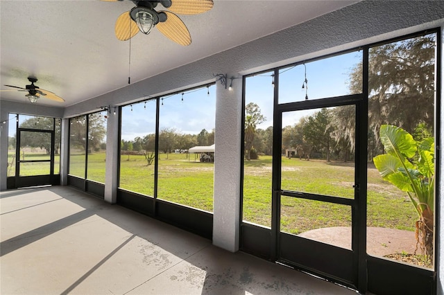 unfurnished sunroom featuring ceiling fan and a wealth of natural light