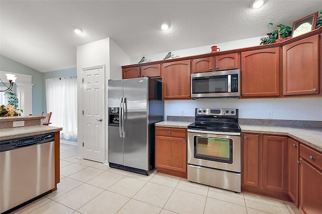 kitchen with light tile patterned floors, stainless steel appliances, lofted ceiling, and brown cabinets