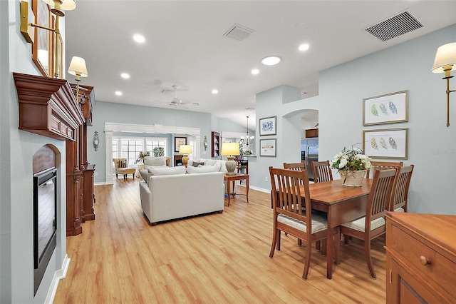 dining area with light wood-type flooring, recessed lighting, visible vents, and a glass covered fireplace