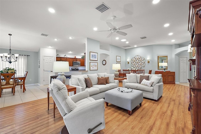 living room with arched walkways, light wood-type flooring, visible vents, and recessed lighting