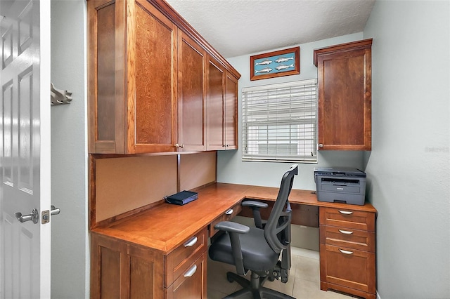 office space featuring light tile patterned floors, a textured ceiling, and built in study area