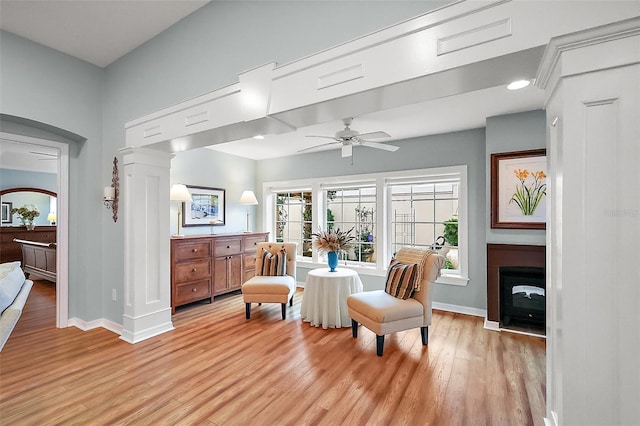 sitting room featuring light wood-type flooring, a fireplace, baseboards, and a ceiling fan