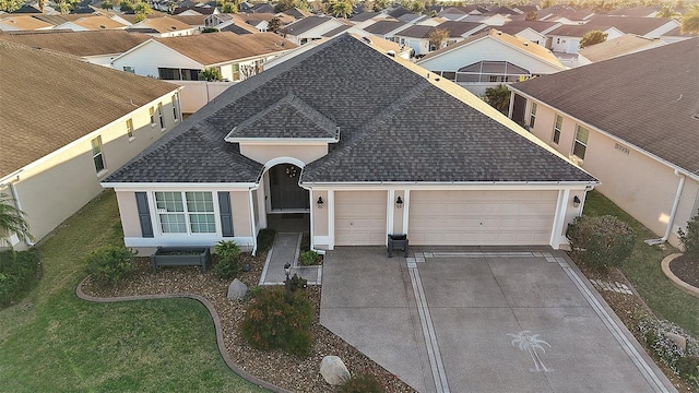 view of front of home with an attached garage, concrete driveway, roof with shingles, a residential view, and stucco siding