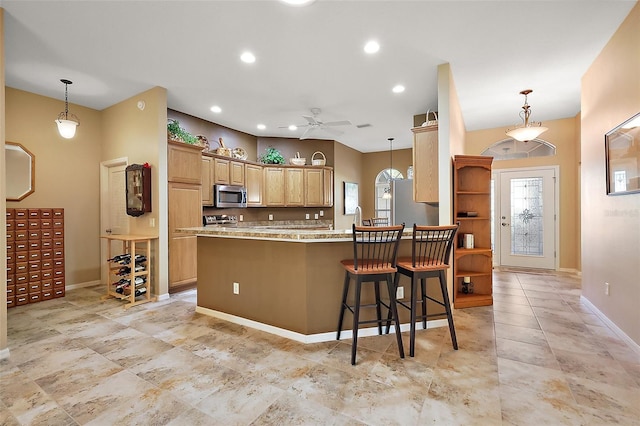 kitchen featuring a peninsula, stainless steel microwave, hanging light fixtures, and recessed lighting