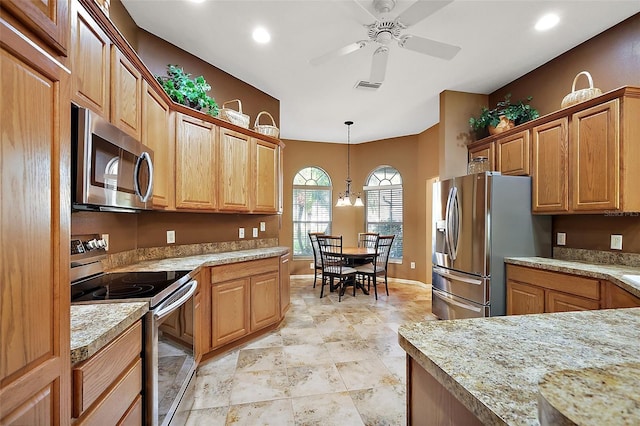 kitchen with pendant lighting, stainless steel appliances, light countertops, visible vents, and ceiling fan