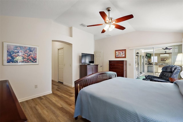 bedroom with visible vents, arched walkways, vaulted ceiling, and wood finished floors