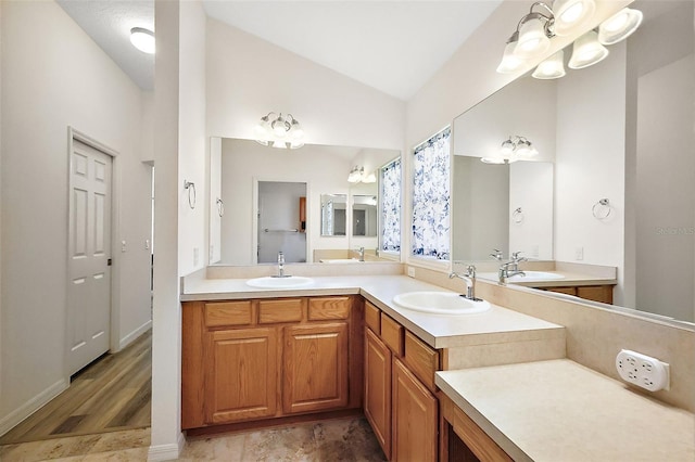 full bathroom featuring lofted ceiling, double vanity, and a sink