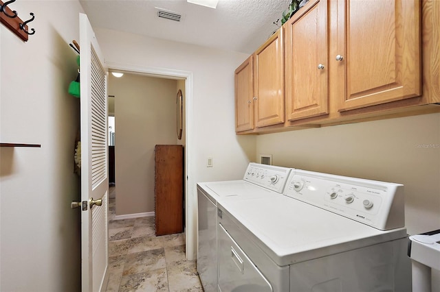 clothes washing area with visible vents, washing machine and dryer, cabinet space, and baseboards