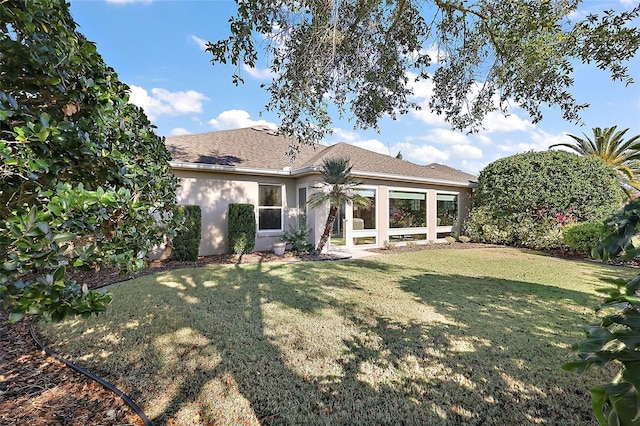 back of property with a lawn and stucco siding