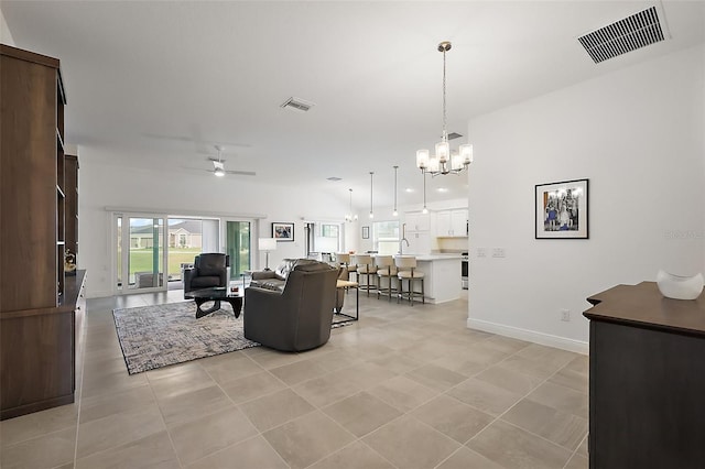 living area featuring light tile patterned floors, visible vents, baseboards, and ceiling fan with notable chandelier