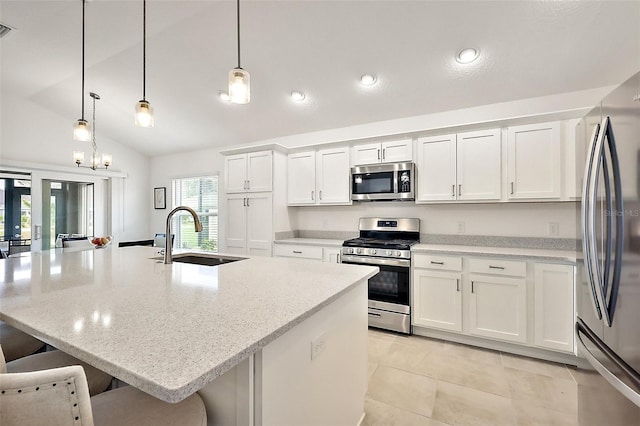 kitchen with appliances with stainless steel finishes, a sink, white cabinetry, and a kitchen breakfast bar