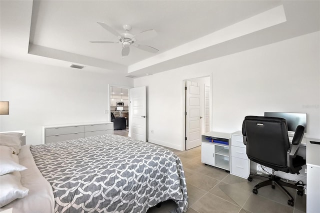 bedroom with ceiling fan, visible vents, baseboards, tile patterned floors, and a raised ceiling