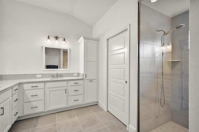 full bath featuring lofted ceiling, tiled shower, vanity, and tile patterned floors