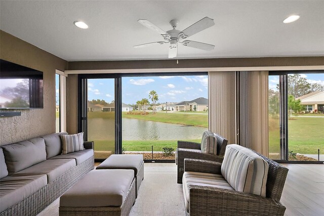 sunroom featuring a water view and ceiling fan