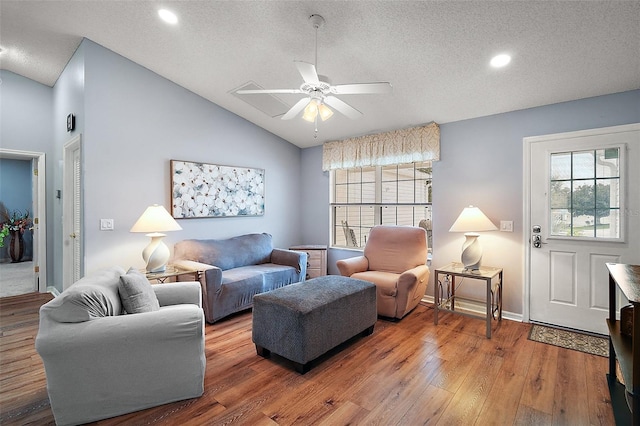 living room with lofted ceiling, ceiling fan, a textured ceiling, baseboards, and hardwood / wood-style floors