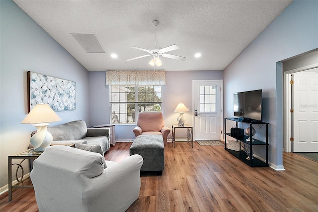 living area featuring lofted ceiling, plenty of natural light, wood finished floors, and visible vents