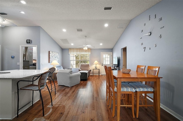 dining area featuring lofted ceiling, ceiling fan, visible vents, and wood finished floors