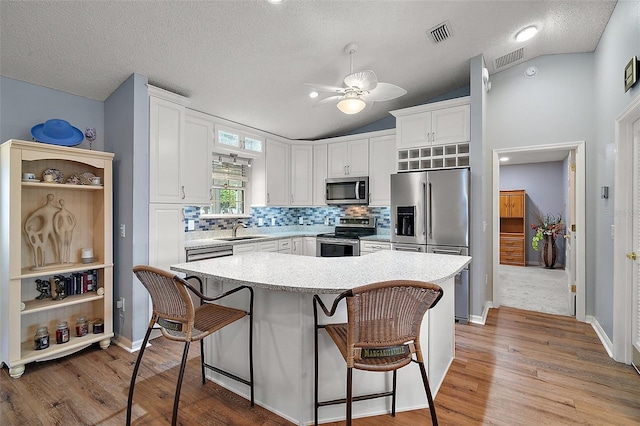 kitchen featuring stainless steel appliances, a breakfast bar, a sink, and white cabinets