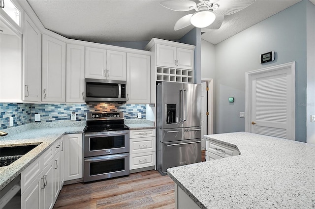 kitchen with a sink, white cabinetry, light wood-style floors, appliances with stainless steel finishes, and tasteful backsplash