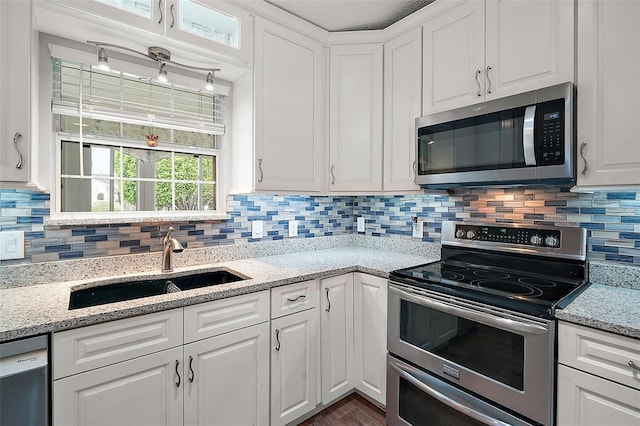 kitchen featuring appliances with stainless steel finishes, a sink, white cabinetry, and tasteful backsplash