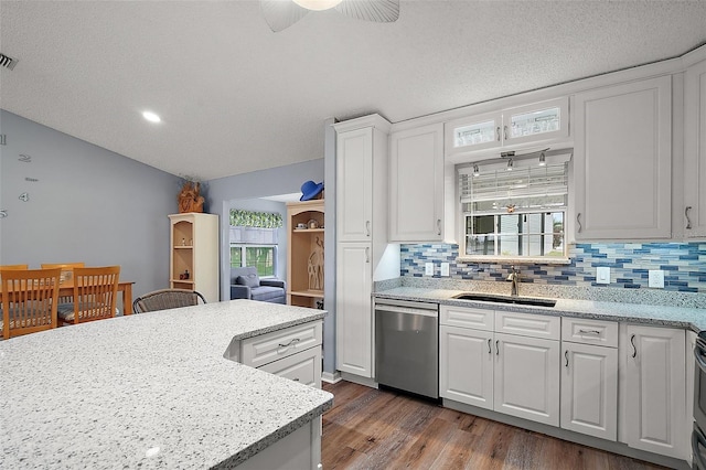 kitchen featuring dark wood finished floors, backsplash, stainless steel dishwasher, white cabinets, and a sink