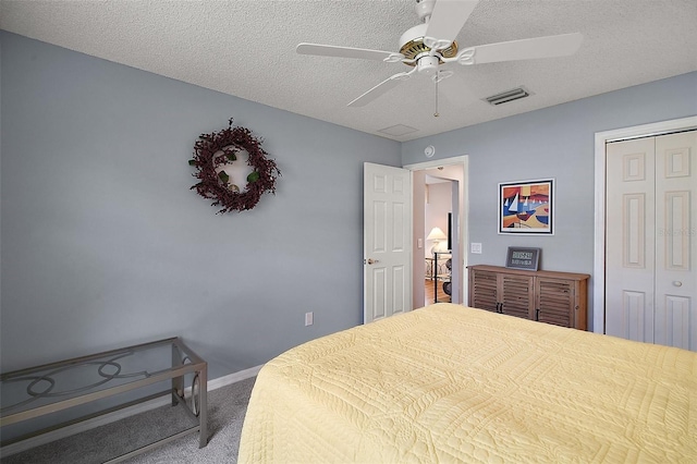 carpeted bedroom with a ceiling fan, a textured ceiling, visible vents, and a closet