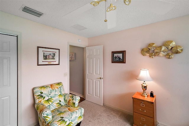 sitting room featuring light carpet, baseboards, visible vents, and a textured ceiling